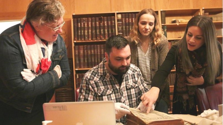 People around table looking at old book