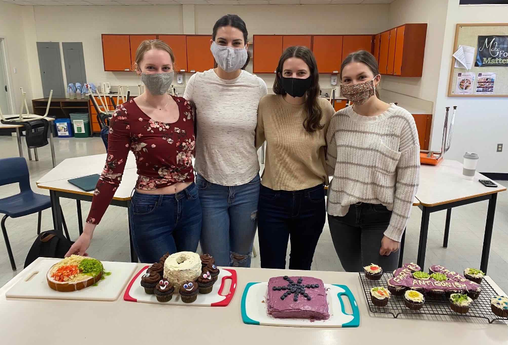 People standing together with food on a table in front of them