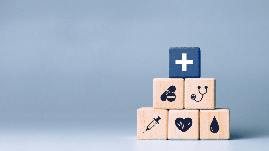 Wooden blocks with healthcare icons stacked in a pyramid
