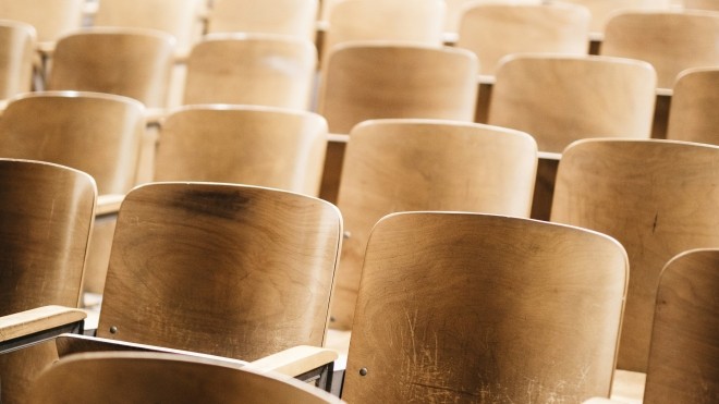 Rows of wooden chairs in a classroom.
