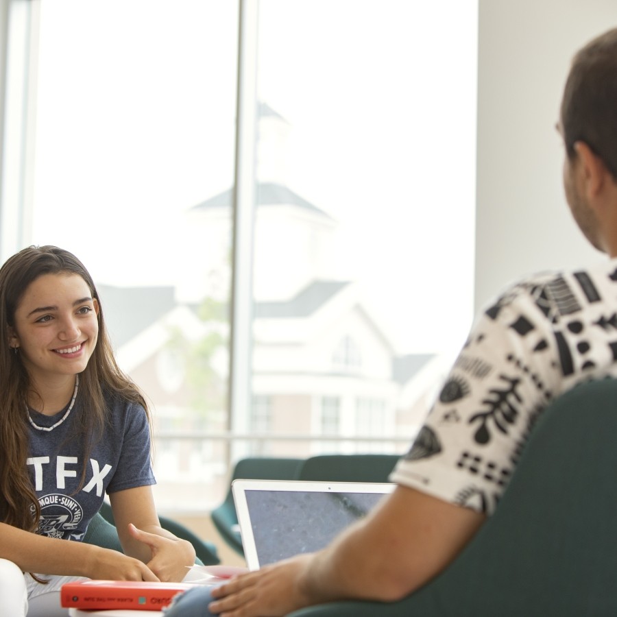 Close up of students studying while sitting on the first floor of Mulroney Hall. 