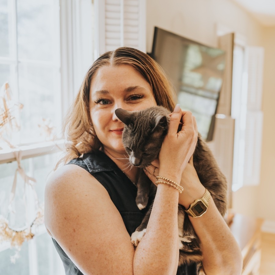A woman with long hair holding a cat next to her face