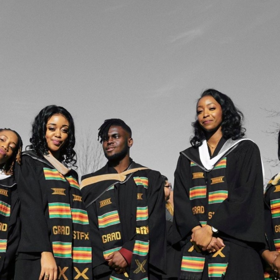 Five people standing wearing graduation robes
