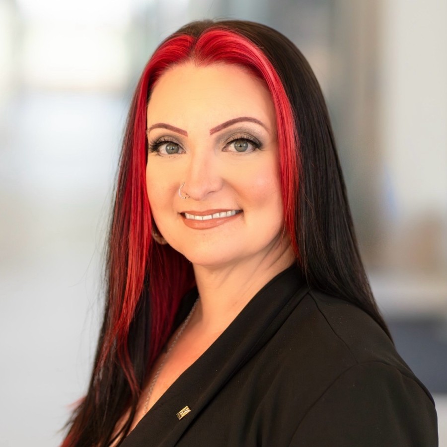 headshot picture of a white woman with long, red and black hair, green eyes and wearing a black blazer
