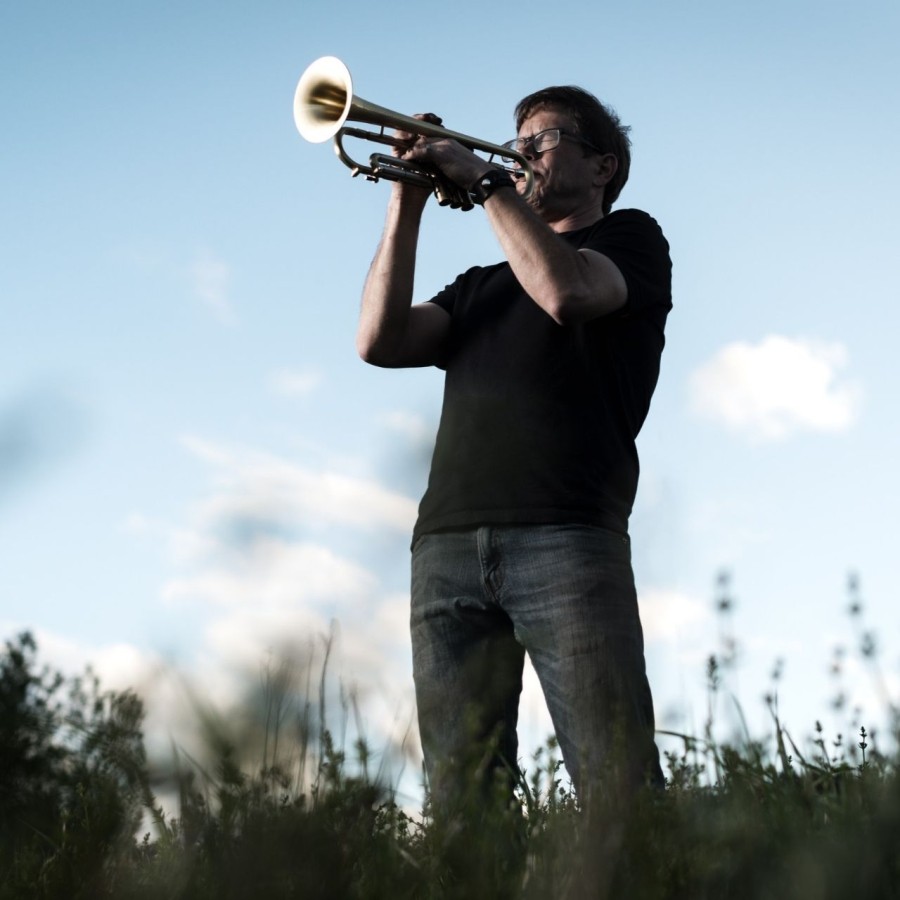 Paul Tynan playing trumpet in open field at dusk