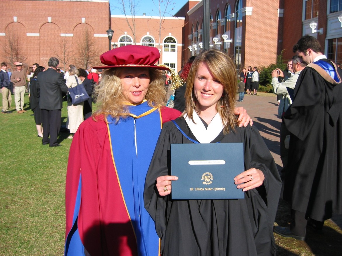 Student showing her diploma in a student convocation. She is side by side with a teacher