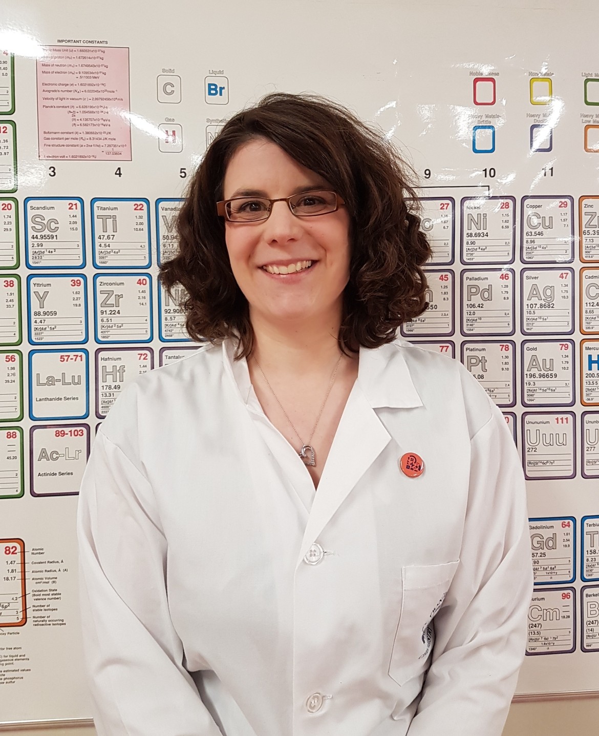 A woman in a lab coat standing in front of a wall