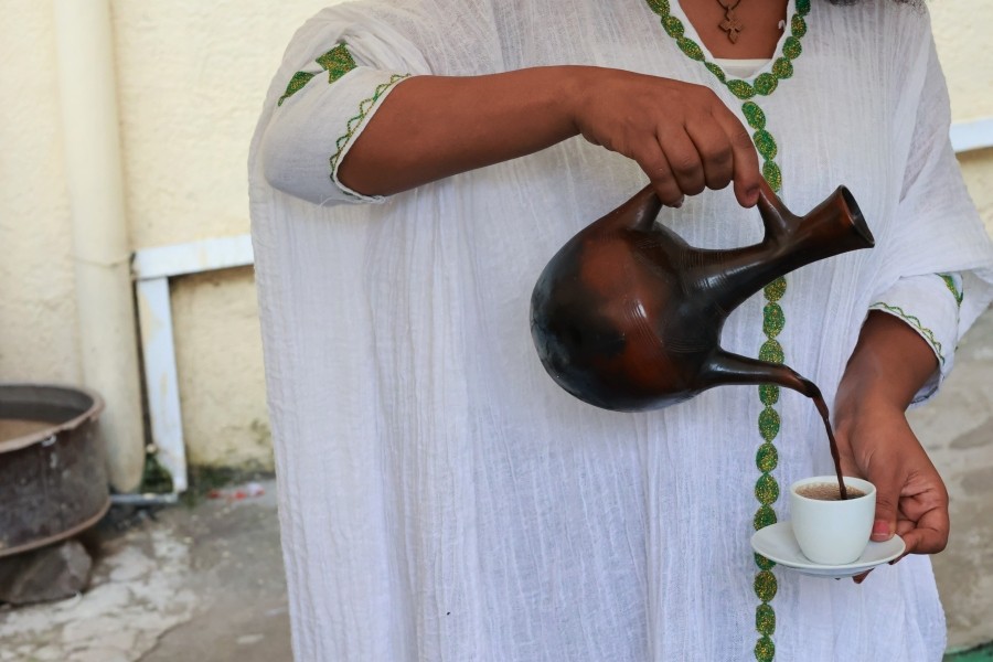 Ethiopian woman pouring coffee using an Ethiopian coffee pot