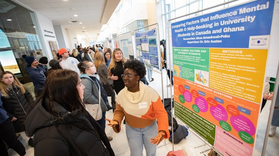 A student explaining a poster to another student in a crowd