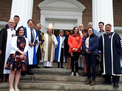 A group of people standing in front of a church entrance smiling