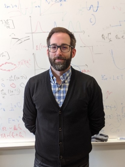 Jesse Maassen's photo. He is standing in front of a whiteboard with equations on it