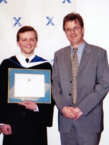 Student showing his diploma, next to a man