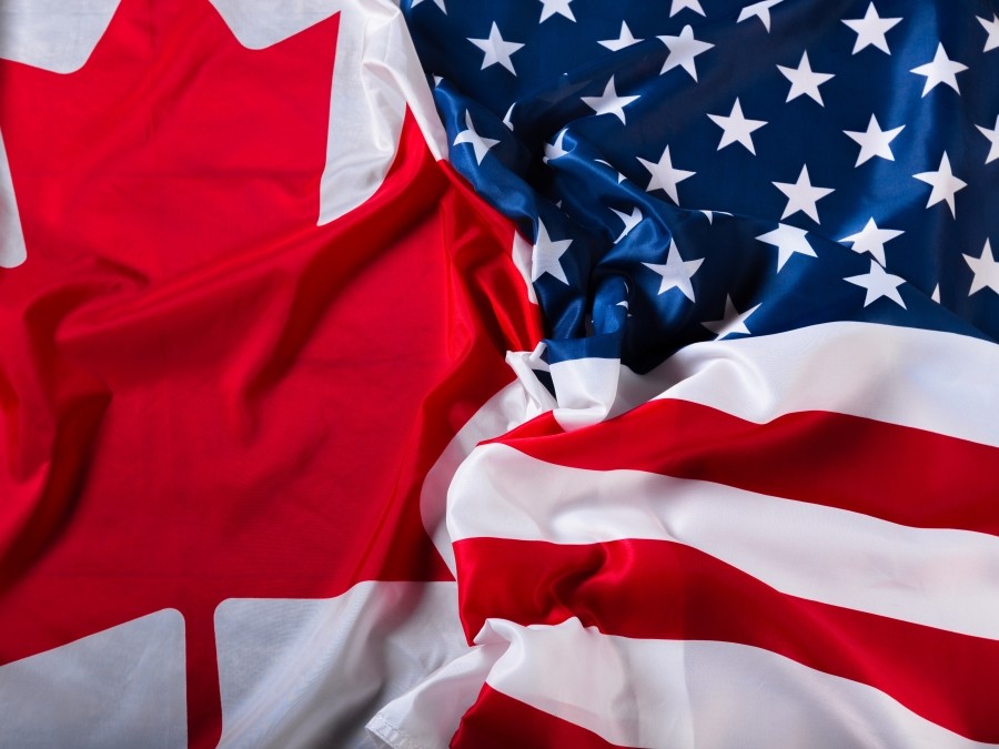 The Canadian flag, which is a red maple leaf on a white background, and the US flag, which is a blue square with white stars on the top and red and white stripes on the bottom, appear in the frame together.