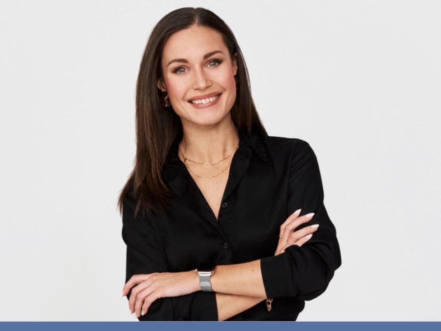 Women with long dark hair wearing a black blazer, arms folded across her chest.