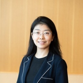 Headshot of Chen Zhang. She is lit by natural light and framed by a green background.